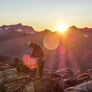 Slunce vychází zpoza temných čtyřtisícových obrů, Lagginhornu a Weissmiesu. Hohlaubgrat, Allalinhorn, Wallis, Alpy, Švýcarsko.