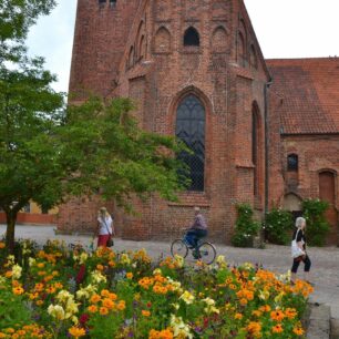 Středověký klášter sv. Petra z červených cihel obklopený pestrobarevnou květinovou výzdobou ve městě Ystad ve Švédsku