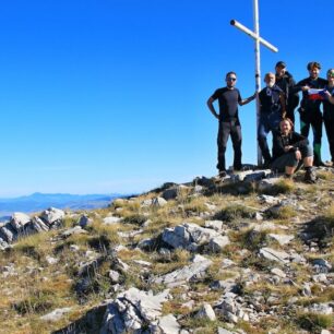 červená boudička, betonový patník a nedaleko stojící vrcholový kříž na špičce Sinjalu, pohoří Dinara, Chorvatsko