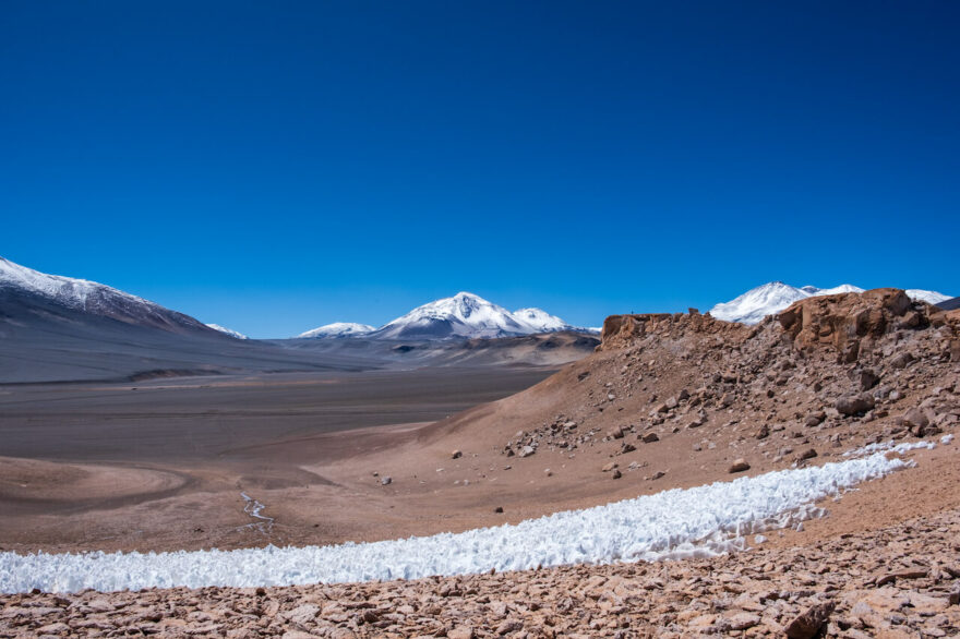 Pole penitentes a v pozadí na levo vulkán El Muerto - 6488m na skalním terase stoji Martin a vyhlizi Ojo del Salado na levo