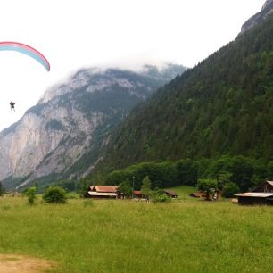 Paraglide přistává na louce ve Stechelbergu, Švýcarsko.